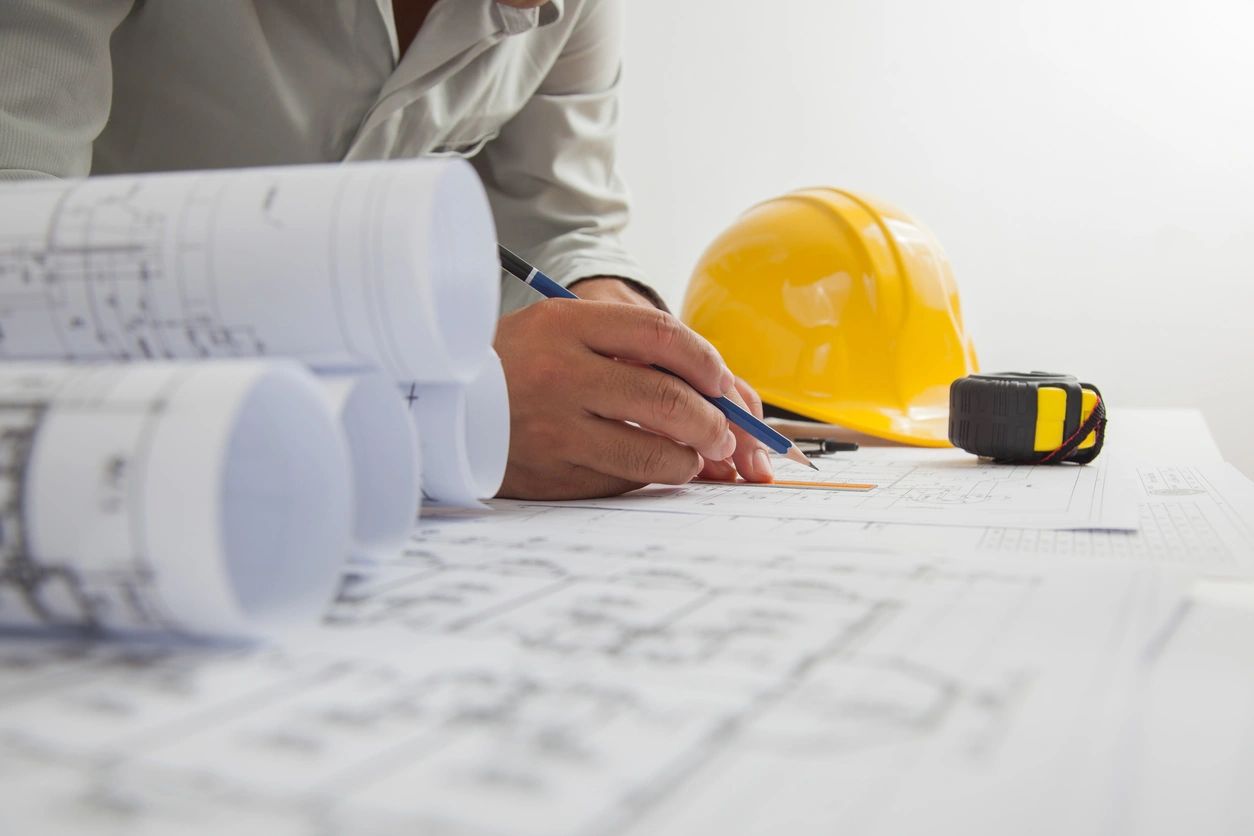 Close up of concentrated male engineer drawing hands working on architectural project at construction site at desk in office